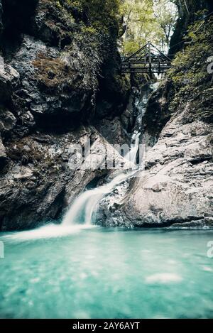 Langer Wasserfall mit Brücke über Wasser zwischen Steinen, Flume in Österreich Bärenschützklamm Stockfoto