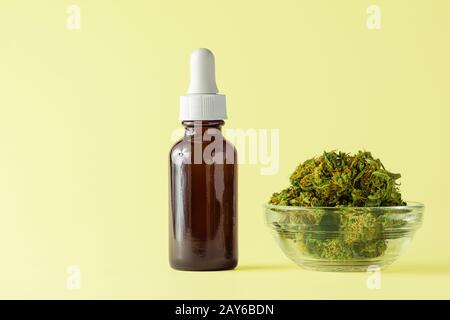 Glasflasche mit CBD- oder THC-Öl mit Hemp- oder Cannabis-Knospen Isoliert auf gelbem Hintergrund mit Copy Space Stockfoto