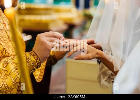 Der Priester legt bei der kirchlichen Hochzeitsfeier den Finger auf die Bräute. Austausch der Ringe. Horizontale Ansicht. Heiratskonzept Stockfoto