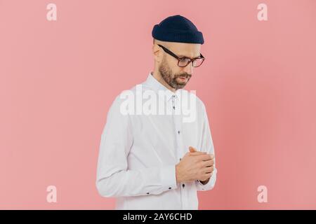 Kontemplative unrasierten Mann hält den Blick nach unten, trägt weiße Hemd, Hut und Brille, in Gedanken tief, versucht Lösung zu machen, denkt daran, wie seine entwickeln Stockfoto