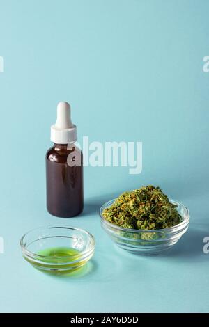 Glasflasche und Gericht aus CBD- oder THC-Öl mit Hemp- oder Cannabis-Knospen auf Aqua Blue Hintergrund Stockfoto