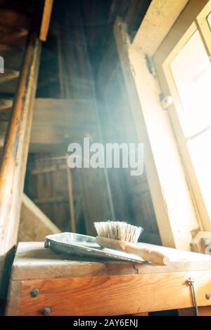 Eine Holzbürste mit natürlichen Borsten und einer Metallschaufel, die auf einer Holzoberfläche liegt Stockfoto