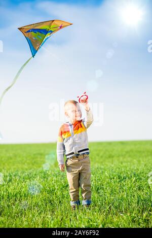 Kleiner Junge spielt mit seinem Kite in einem grünen Feld. Stockfoto