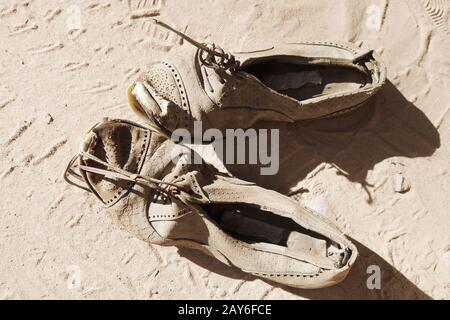 Altes Paar Schuhe auf Sand Stockfoto