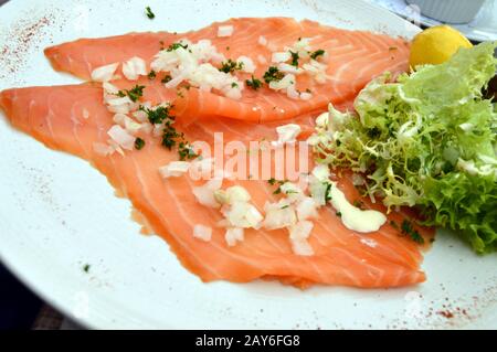 Scheibe Räucherlachs mit frischen Zwiebeln und Gurke Salat Stockfoto