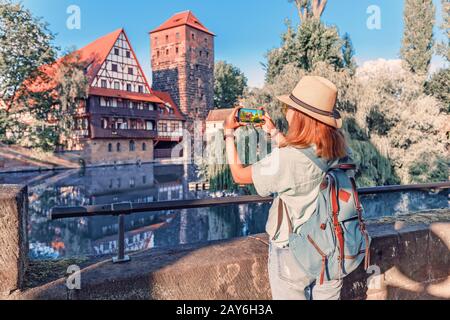 Fröhliche asien-touristin fotografieren in der Altstadt von Nürnberg und Pegnitz. Travel Blogger in Deutschland Konzept Stockfoto