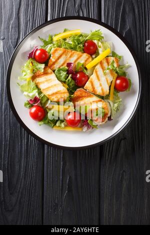 Zyprischer Salat mit gegrilltem Halloumi-Käse, Tomaten, Paprika und Salat in einem Teller auf dem Tisch. Vertikale Draufsicht von oben Stockfoto