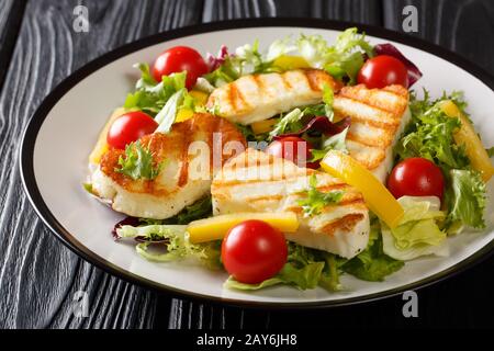 Lecker Imbisssalat Gegrillter Halloumi-Käse mit frischem Gemüse auf dem Teller auf dem Tisch. Horizontal Stockfoto