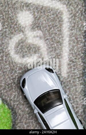 Spielzeugauto parken auf einem Behinderten-Parkplatz auf dem Teppich der Autostadt Stockfoto