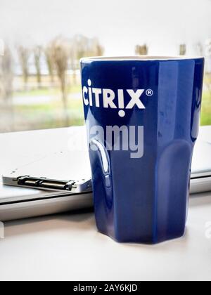 Kaffeebecher mit Citrix-Logo-Laptop und SSD-Laufwerk auf dem Tisch im modernen IT-Büro. Stockfoto