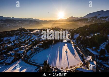 Atemberaubender Sonnenuntergang über dem Dorf Crans Montana, über dem Rhonetal, im Wallis, Schweiz an einem sonnigen Winterabend. Stockfoto