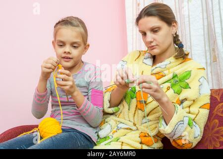 Mutter und Tochter sieben-Jahres-Strick auf den Nadeln sitzen auf der couch Stockfoto