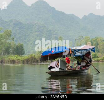 Vietnamesischer Souvenirverkäufer, der auf einem Boot am Roten Fluss in Hanoi, Vietnam verkauft Stockfoto