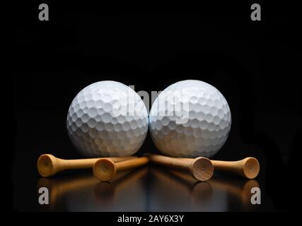 Golf Stillleben. Zwei Golfbälle mit T-Shirts, die auf einer schwarzen reflektierenden Oberfläche liegen. Niedriger Winkel mit Kopierbereich. Stockfoto