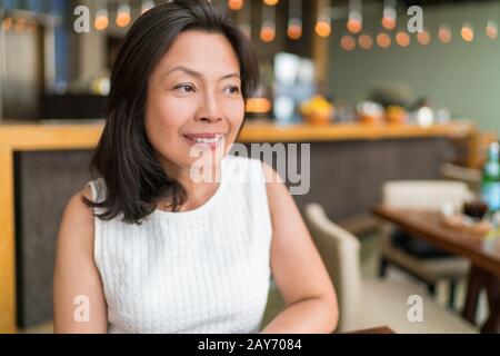 Fröhliche gesunde asiatische Geschäftsfrau mittleren Alters, die sich im Restaurant entspannen kann. Schöne reife chinesische Geschäftsfrau Portrait im schicken Restaurant in Shanghai, China. Hautpflege im Alter von Schönheit. Stockfoto