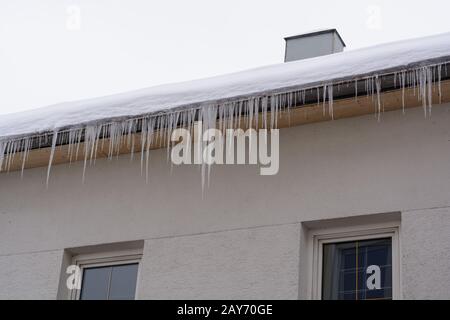 Eiszapfen und Schnee hängen idyllisch vom Dach eines Hauses Stockfoto