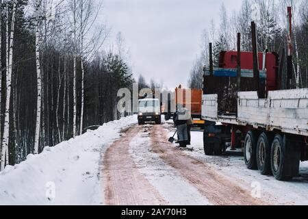Holz-LKW beladen mit Protokollen, die verschneiten Straße fahren Stockfoto
