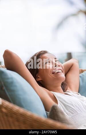 Home Lifestyle Frau entspannend genießen Sie luxuriöse Sofamöbel auf der Terrasse im Freien Wohnzimmer oder Hotel. Fröhliche Dame, die auf bequemen Kissen liegt. Schönes junges asiatisches china-mädchen. Stockfoto