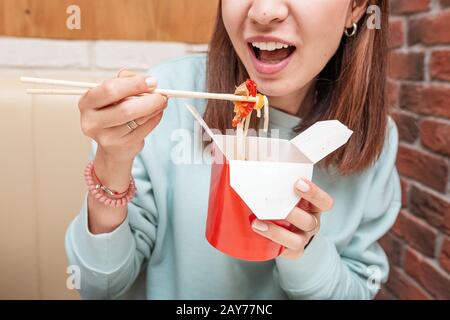 Frau, die Wok Nudeln im asiatischen Restaurant isst Stockfoto