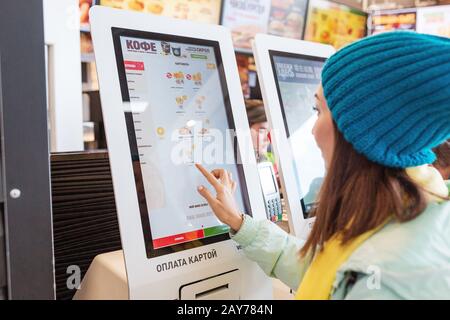 03. Mai 2019, Moskau, Russland: Frau bestellt Mahlzeit im elektronischen Touchscreen Terminal-Menü im Fastfood-Restaurant Burger King Stockfoto