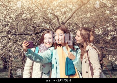 Drei junge hübsche Mädchen machen selfie Foto im Frühlingspark, Sisterhood Konzept Stockfoto