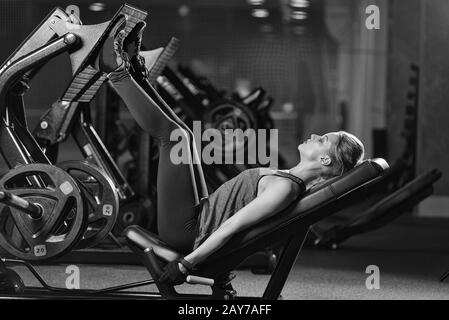 Sportliche Frau mit Gewichten-Presse-Maschine für die Beine. Fitness-Studio. Stockfoto