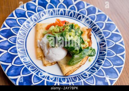 Herzhafte Crêpes mit Lachs und pochiertem Ei Stockfoto