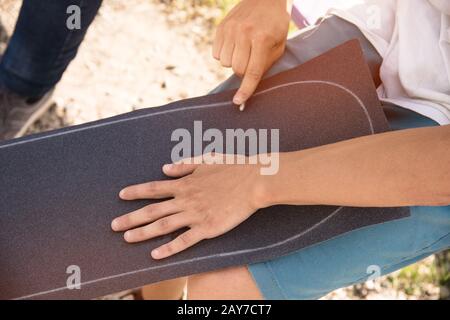 Junge kleben das Griptape auf ein Skateboard Stockfoto