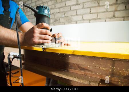 Professionelle Tischler verarbeiten die Kunststoffkanten der Arbeitsplatte. Das Konzept der Möbelherstellung Stockfoto