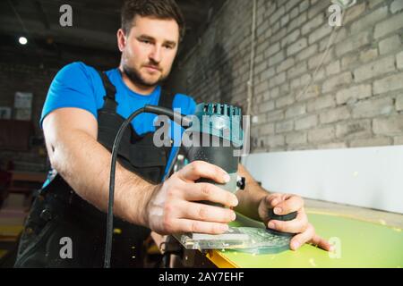 Professionelle Tischler verarbeiten die Kunststoffkanten der Arbeitsplatte. Das Konzept der Möbelherstellung Stockfoto