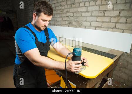 Professionelle Tischler verarbeiten die Kunststoffkanten der Arbeitsplatte. Das Konzept der Möbelherstellung Stockfoto