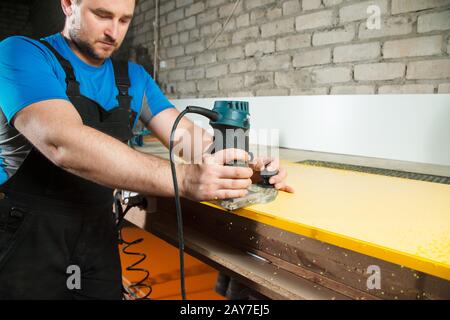 Professionelle Tischler verarbeiten die Kunststoffkanten der Arbeitsplatte. Das Konzept der Möbelherstellung Stockfoto