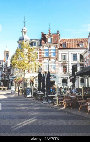 Venlo, Limburg-Niederlande - 13. Oktober 2018: Straße mit Cafés, Restaurants und Bars im historischen Zentrum der niederländischen Stadt. Leute, die in den Gärten sitzen. Vertikales Foto. Stockfoto