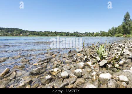 Bank vom Tegernsee in Bayern mit Schilf und Steinen Stockfoto