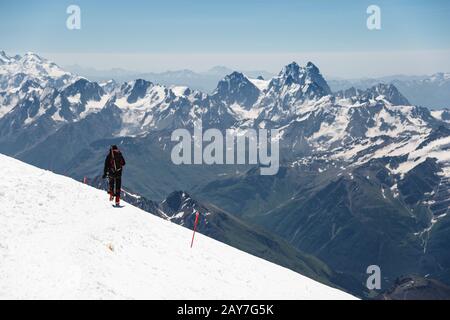 Bergsteiger in den Bergen schlendern am Schneehang entlang vor dem Hintergrund schneebedeckter Gipfel Stockfoto