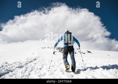 Bergsteiger steigt bergauf, um einen vom Berg kommenden Bergsturm zu treffen Stockfoto