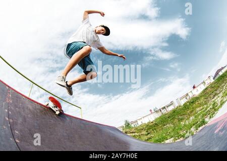 Junger Skater springt von der Rampe hinunter Stockfoto