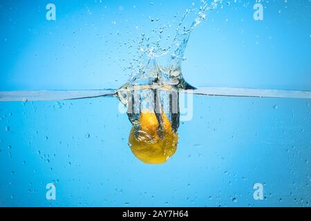 Einzelne Zitrone wird in Wasser fallen gelassen Stockfoto
