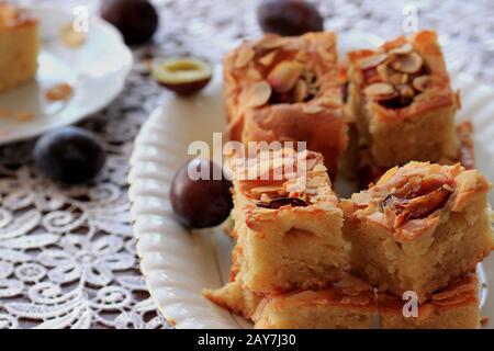 Kuchen mit Pflaumen und Mandelflocken. Hausgemachter Kuchen. Kuchen mit Obst. Ein köstliches und leichtes Dessert. Pflaumenkuchen. Schwammkuchen mit Früchten. Stockfoto