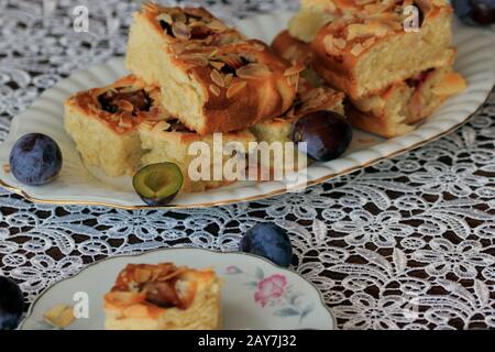 Kuchen mit Pflaumen und Mandelflocken. Hausgemachter Kuchen. Kuchen mit Obst. Ein köstliches und leichtes Dessert. Pflaumenkuchen. Schwammkuchen mit Früchten. Stockfoto