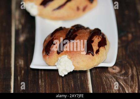 Hausgemachte Donuts mit Schlagsahne. Leckere süße Brötchen. Hausgemachtes Brot. Stockfoto