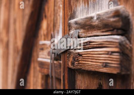 Altes einfaches Schloss an einer Holztür, geschlossen mit einer rustikalen Metallstiftverriegelung an einer alten Tür aus Holz Stockfoto