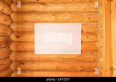 Leere Fahne aus Stoff hängende Holzblockhauswand aus Zylinderstämmen Stockfoto