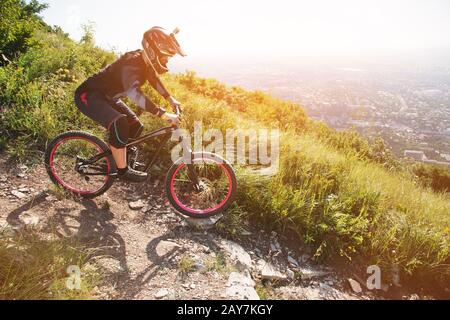 Ein Fahrer in einem Helm reitet auf einem Schotterweg von einem Berghang auf einem Mountainbike-Rad Stockfoto