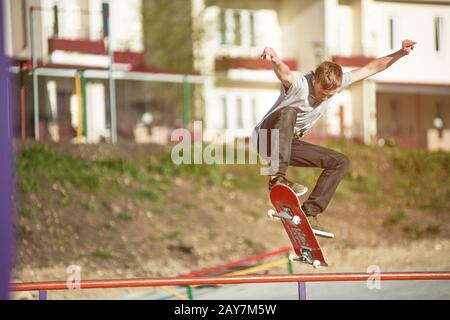 Ein Teenager-Skateboarder macht einen Ollie-Trick in einem Skatepark am Stadtrand Stockfoto