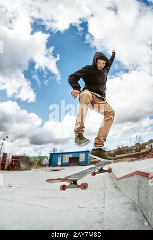 Ein junger Skateboarder macht Wallie in einem Skatepark und springt mit einem Coup auf einem Skateboard in die Luft Stockfoto