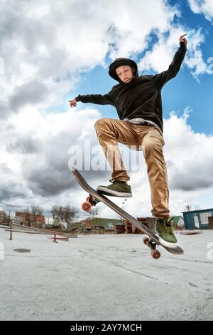 Ein junger Skateboarder macht Wallie in einem Skatepark und springt mit einem Coup auf einem Skateboard in die Luft Stockfoto