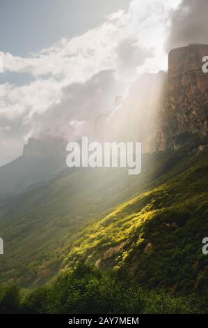 Vertikale Landschaft, das Sonnenlicht, das durch die Wolken bricht, beleuchtet lokal den Handabschnitt am Fuß des Kaukasus Stockfoto