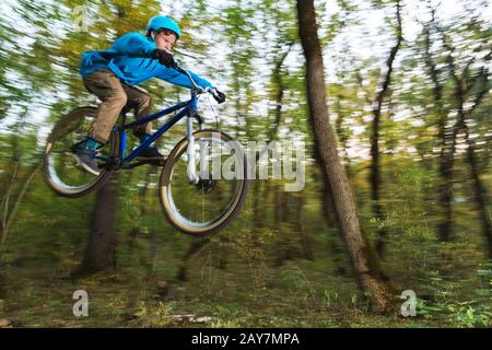 Ein junger Kerl in einem Helm fliegt auf einem Fahrrad, nachdem er von einem Kicker gesprungen ist Stockfoto