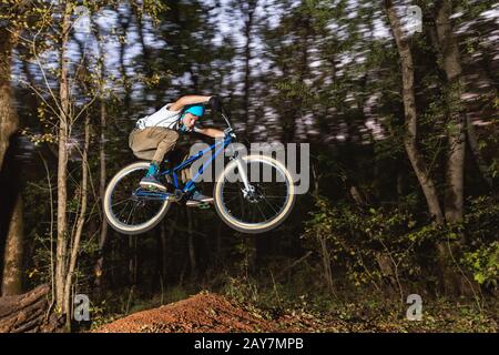 Ein junger Kerl in einem Helm fliegt auf einem Fahrrad, nachdem er von einem Kicker gesprungen ist Stockfoto